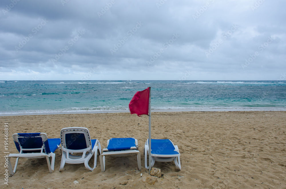 Empty sundeds on dangerous resort beach with red flag Empty sundeds on dangerous resort beach with red flag