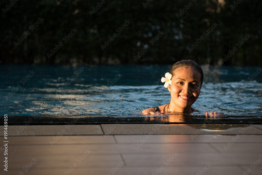 Fototapeta premium Smiling portrait of beautiful woman in swimming pool,Beautiful young woman relaxing in spa swimming pool.