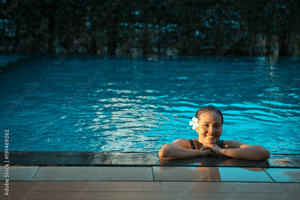 Smiling portrait of beautiful woman in swimming pool,Beautiful young woman relaxing in spa swimming pool.
