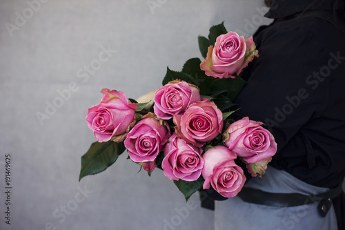 The big bouquet of beautiful pink roses in woman hands on gray background