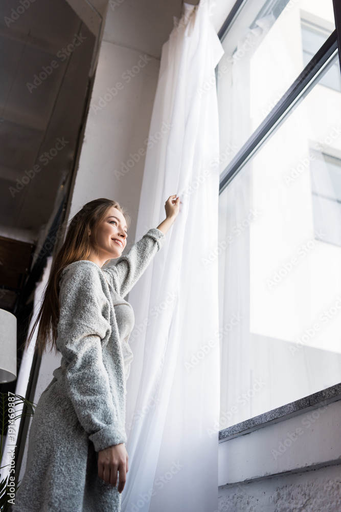 bottom view of girl standing near window and opening tulle bottom view of girl standing near window and opening tulle