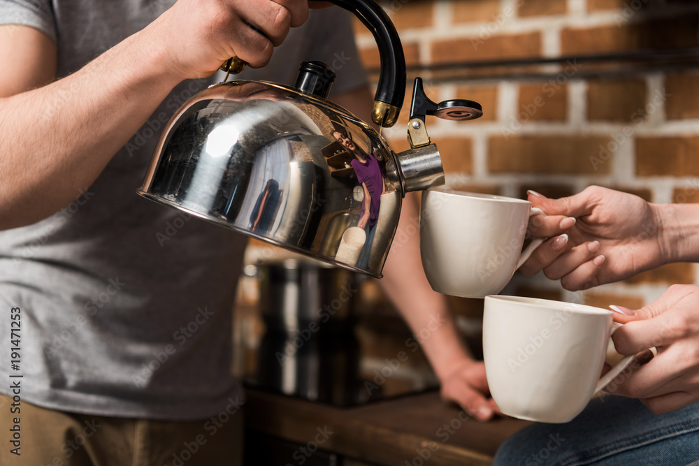 cropped image of boyfriend pouring coffee in cups cropped image of boyfriend pouring coffee in cups