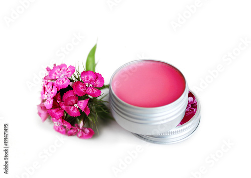 pink lip balm in the container with a pink flower near it