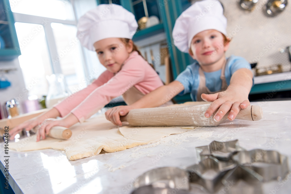 cute little kids preparing dough and smiling at camera in kitchen cute little kids preparing dough and smiling at camera in kitchen