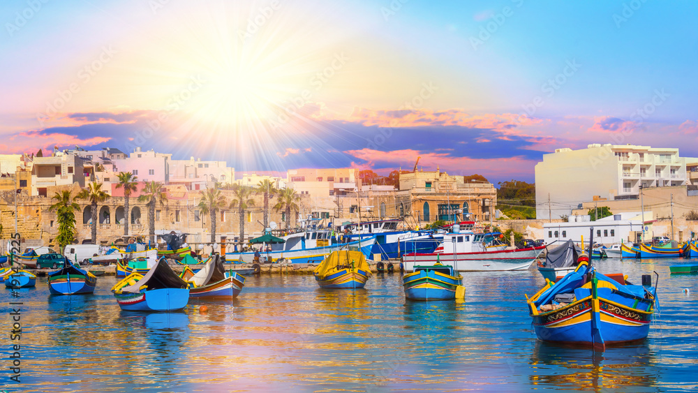 Beautiful panorama of Valletta harbor in Malta, with boats and architecture illuminated by sunset light