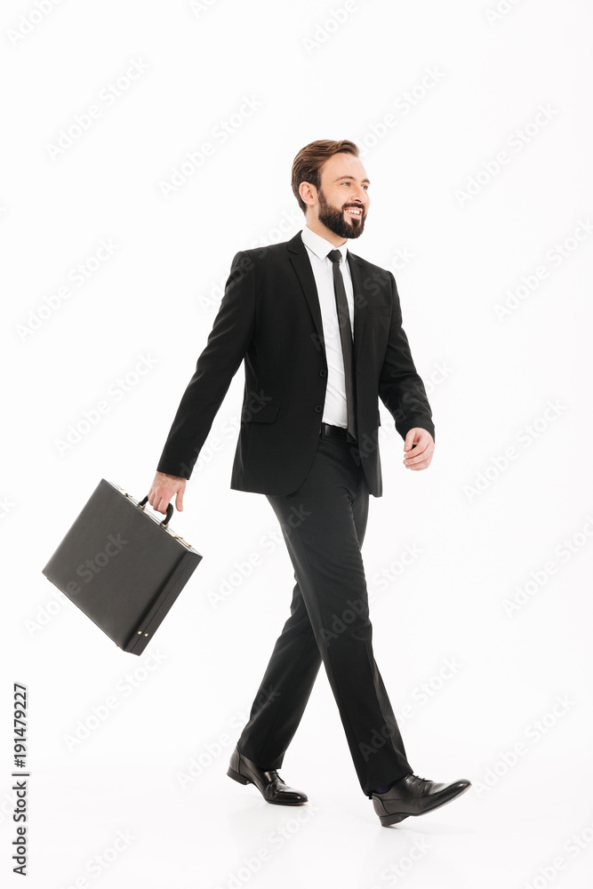 Full-length photo of smiling ambitious man in business suit going on meeting with black diplomat in hand, isolated over white background Full-length photo of smiling ambitious man in business suit going on meeting with black diplomat in hand, isolated over white background