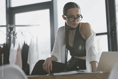 stylish fashion designer sitting on work desk at office