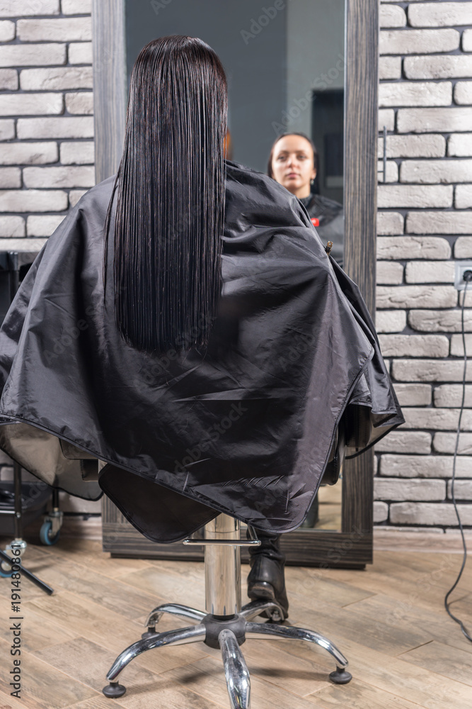 Naklejka premium Female young client with long wet hair sitting in armchair in front of the mirror