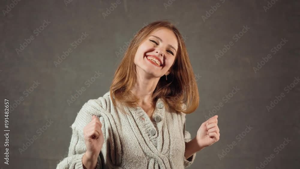 Cheerful caucasian girl showing her thumbs up in the gray background, concept of happiness and satisfaction Cheerful caucasian girl showing her thumbs up in the gray background, concept of happiness and satisfaction