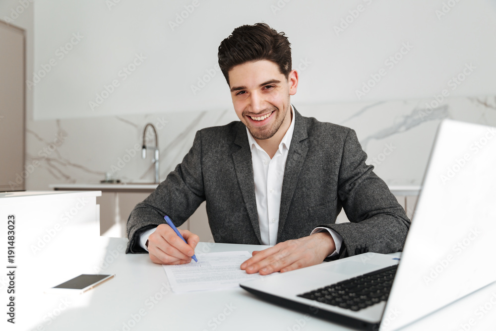 Young cheerful businessman writing notes Young cheerful businessman writing notes