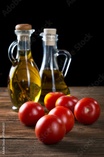 tomatoes and bottles of olive oil on rustic table
