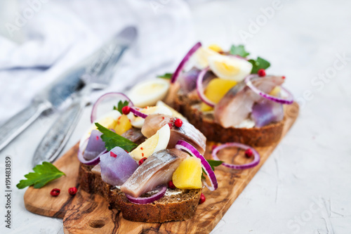 Open sandwich (smorrebrod) with herring, onion, potato and eggs photo