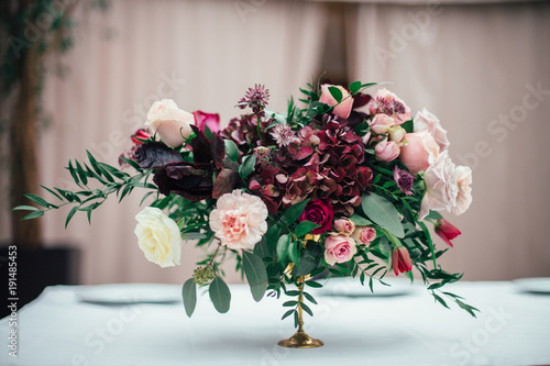 Tableau sur toile Rich bouquet of red, pink and white roses and greenery stands on the table in a