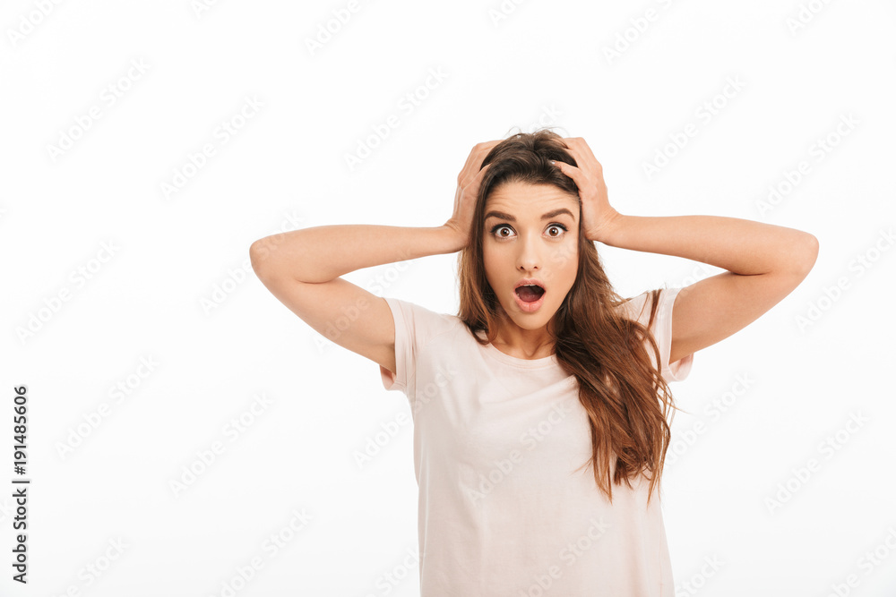 Shocked brunette woman in t-shirt holding her head Shocked brunette woman in t-shirt holding her head