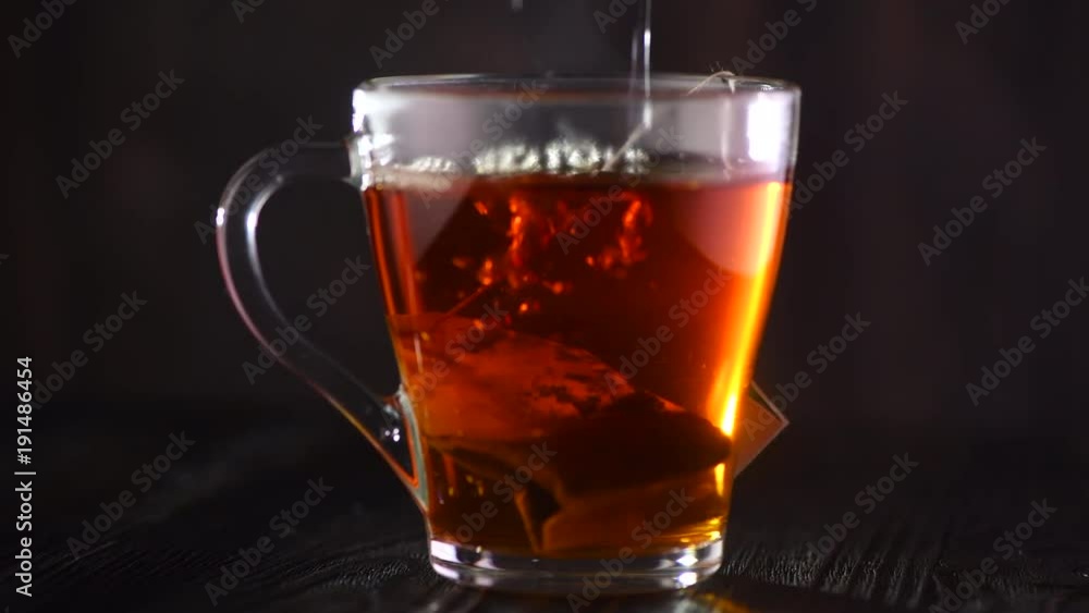 Tea in transparent glass cup rotated on dark wood table background. 4K UHD video footage. 3840X2160 Tea in transparent glass cup rotated on dark wood table background. 4K UHD video footage. 3840X2160