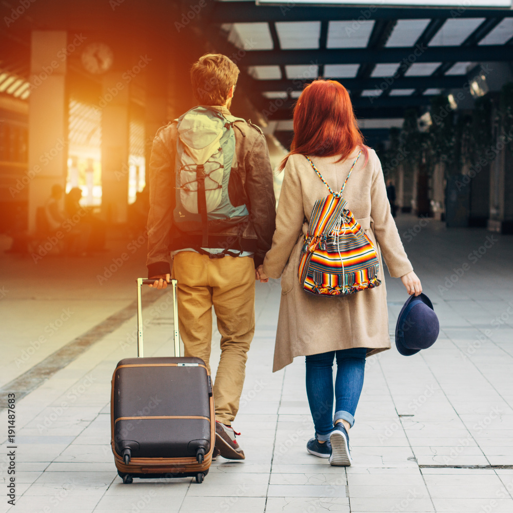 Fototapeta premium Rear view of amorous hipster couple walking down station and chatting outdoors. Holyday and weekend concept