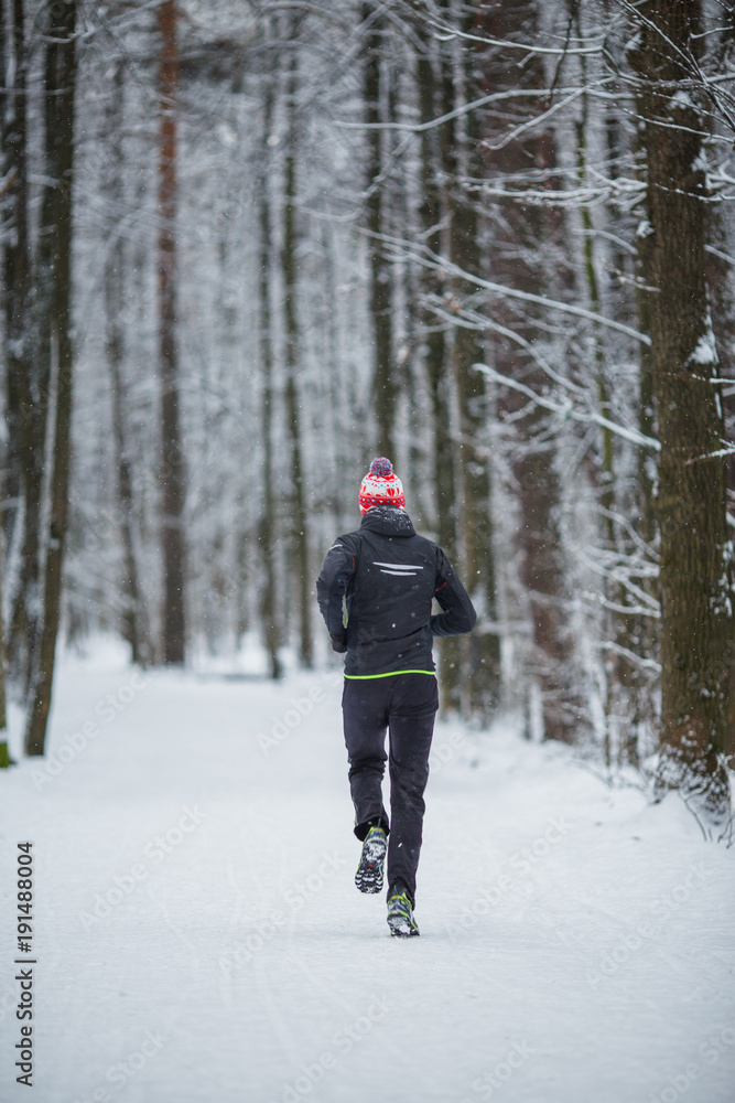 Photo from back of running athlete among trees in winter forest