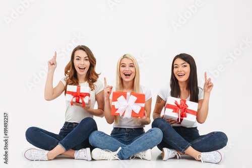 Three young excited girls friends holding surprise gifts
