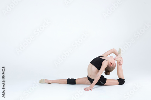 Rhythmic gymnastics caucasian ballet dancer girl in black suite stretching in black costume on white background isolated showing flexible fitness