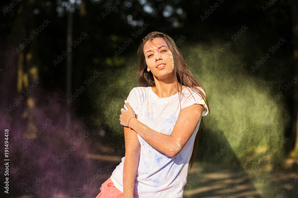 Wonderful tanned asian woman dressed in white shirt, playing with green and purple Holi paint Wonderful tanned asian woman dressed in white shirt, playing with green and purple Holi paint