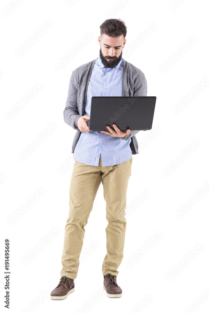 Front view of serious businessman holding and looking at laptop computer. Full body length portrait isolated on white studio background. Front view of serious businessman holding and looking at laptop computer. Full body length portrait isolated on white studio background.
