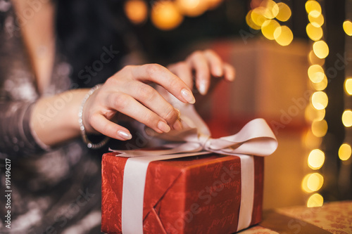 The beautiful girl sits on the floor and opens a present