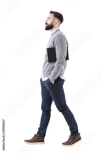 Confident serious businessman walking and carrying planner under arms. Side view. Full body length portrait isolated on white studio background.  © sharplaninac