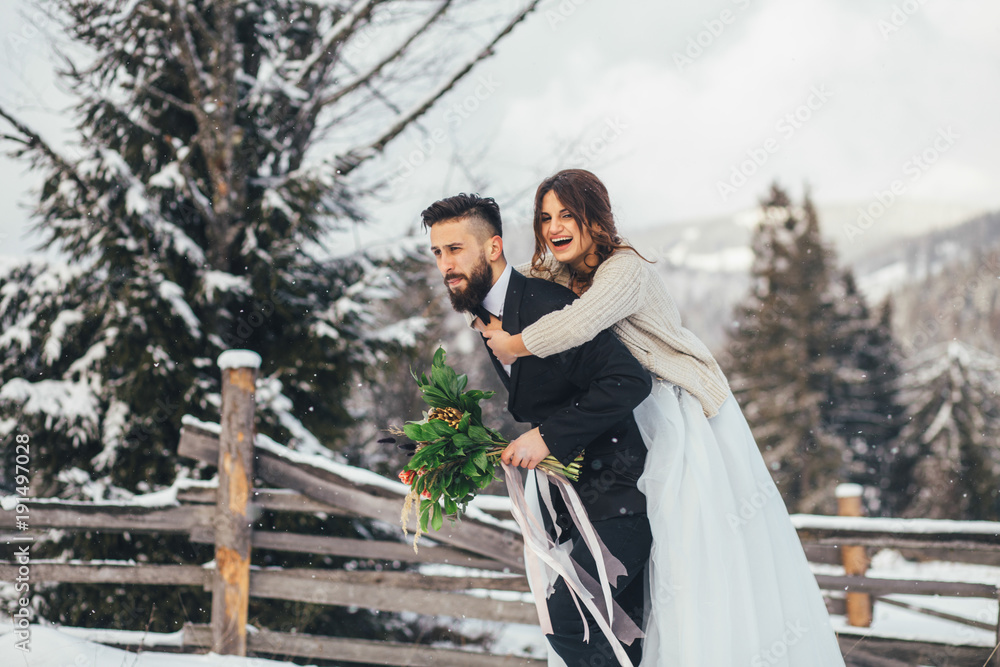 Naklejka premium Bearded man and his lovely bride pose on the snow in a magic winter forest