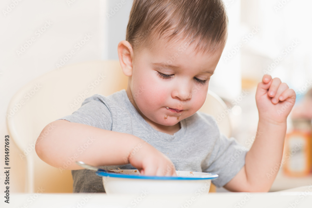 the kid eats buckwheat porridge in the kitchen