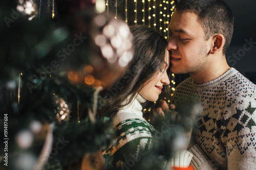 The lovely couple in love embracing near christmas tree