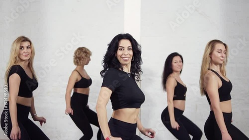 Group of female dancers learning how to move their bodies when dancing bachata. photo