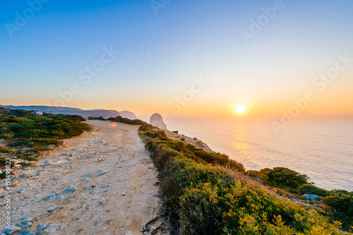 Amazing stunning unbelievable sunset at atlantic ocean in Portugal. Cape Rock fantasy seascape. View from big height at colorful scenic sea with rocks and mountains in evening. Tropical paradise.