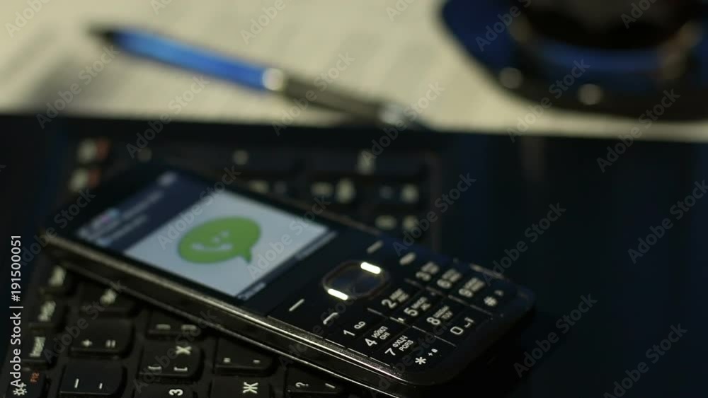 Closeup of man in office answering incoming call on black button mobile phone