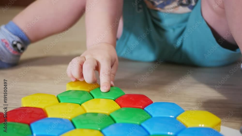 A cute child collects a picture from large multi-colored details. Playing with a puzzle A cute child collects a picture from large multi-colored details. Playing with a puzzle
