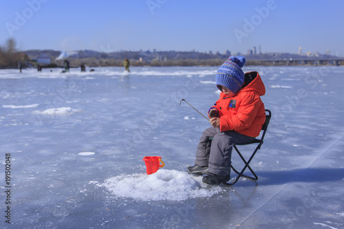 a little boy is fishing on a frozen lake