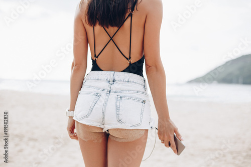 cropped view of girl with smartphone at beach