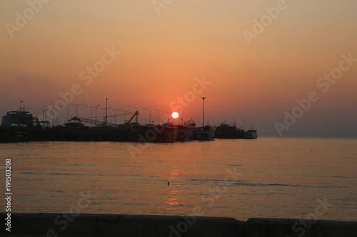 Sunset Ferry Pier Many boats are parked. And the sun is red. © Nantawit