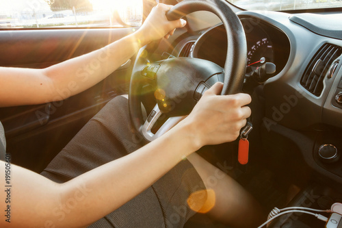 Female hands hold the steering wheel  close-up. A woman is driving a car.