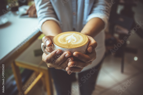 Woman hand holding coffe cup in coffee shop photo