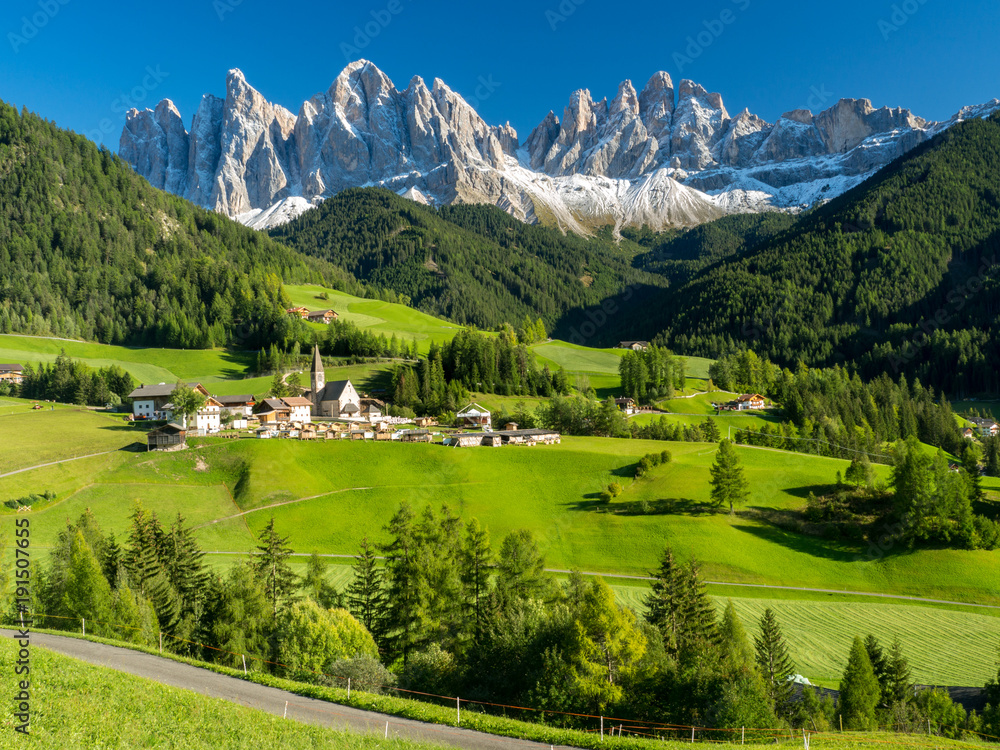 Val di Funes valley, Santa Maddalena touristic village, Dolomites, Italy, Europe. September, 2017. Green grass and blue sky.