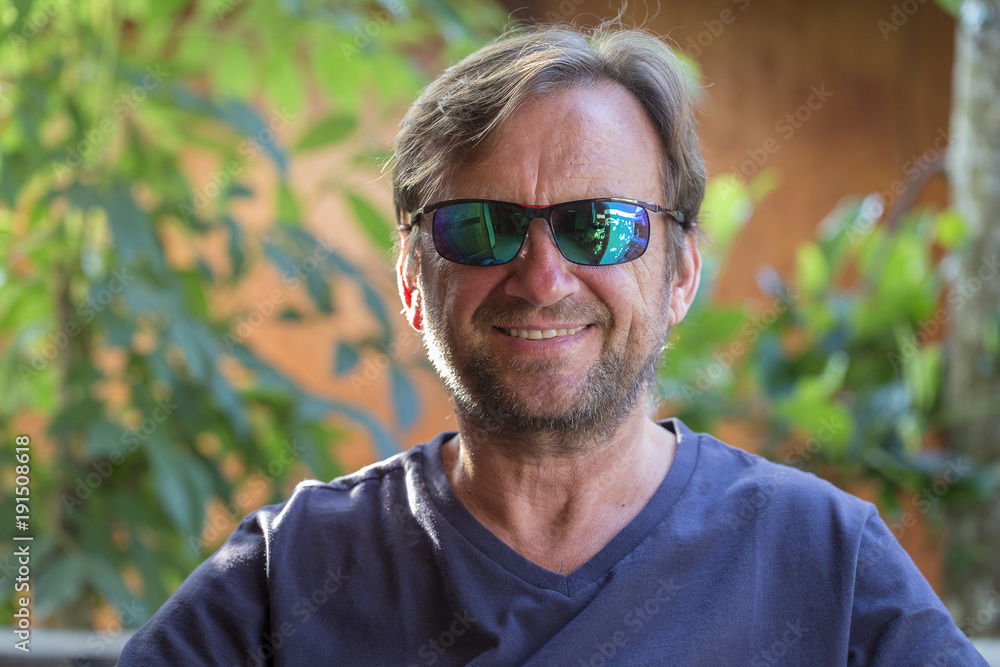 Portrait of an unshaven middle-aged man in sunglasses relaxing on the nature in summer day Portrait of an unshaven middle-aged man in sunglasses relaxing on the nature in summer day