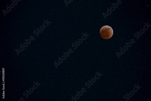 ull red eclipse moon in clear night sky with shiny stars for background