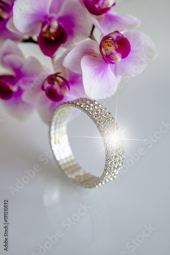 Zirconium bracelet lies on the background of purple orchids photo