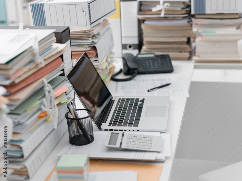 Office desk with piles of paperwork Office desk with piles of paperwork