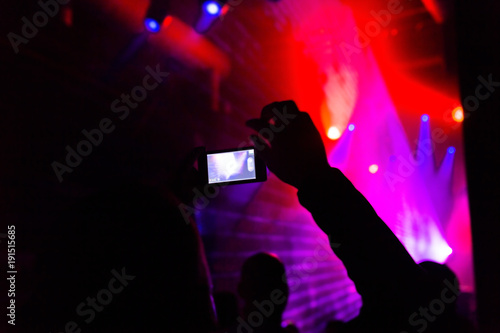 Man taking photo mobile phone of silhouettes crowd
