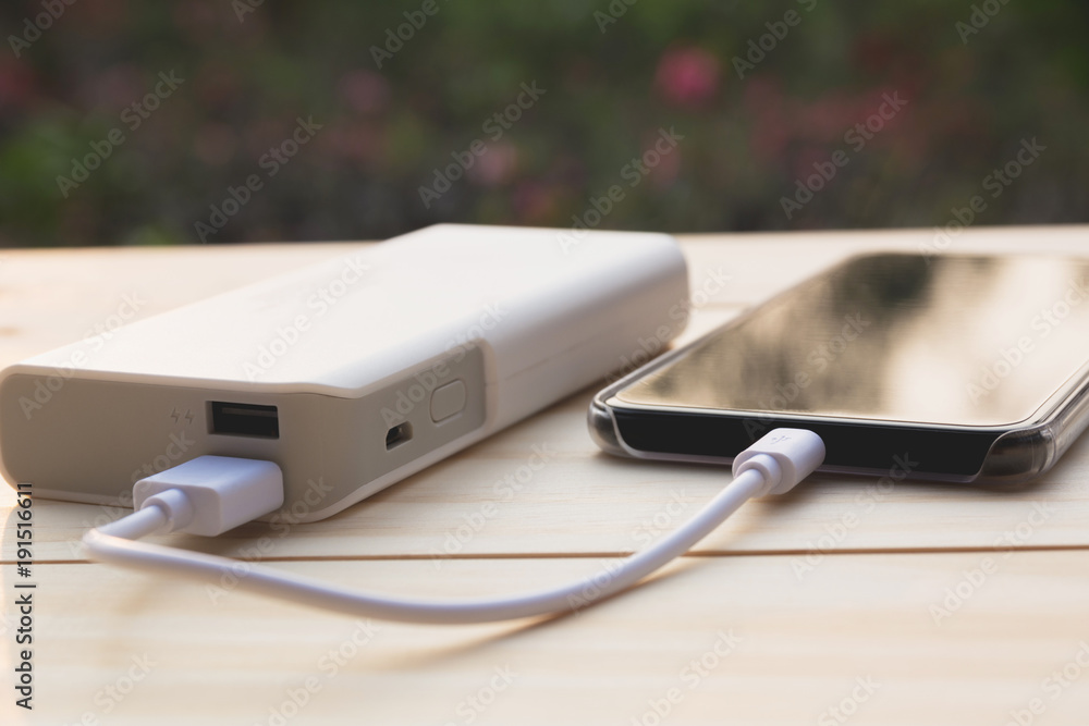Mobile smart phones charging with power bank on desk. Mobile smart phones charging with power bank on desk.