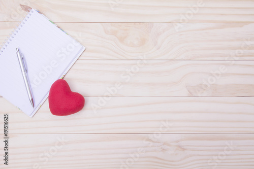 Red heart with pen and empty note on wooden table for valentine day concept.