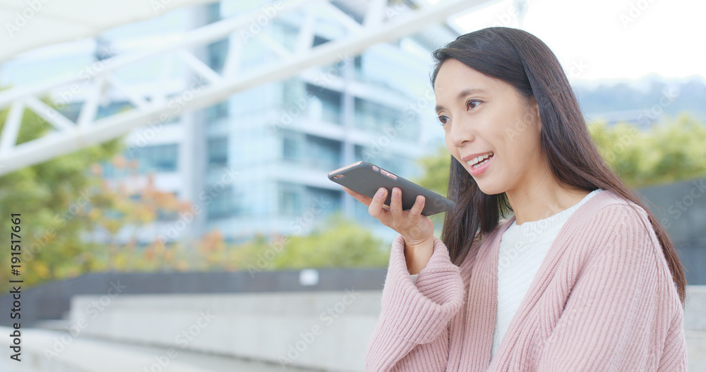 Fototapeta premium Woman sending audio message on cellphone at outdoor