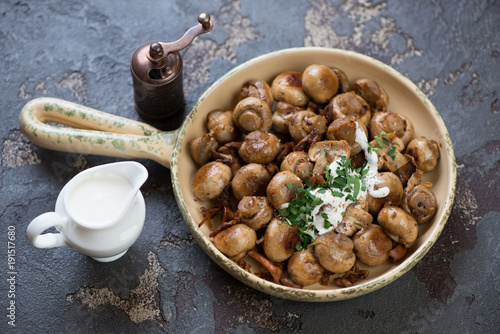 Frying pan with roasted champignon and chanterelle mushrooms on a brown stone background, studio shot