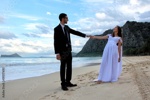 wedding dance of young bride and groom at the beach  mountain and blue sky with clouds and the back
